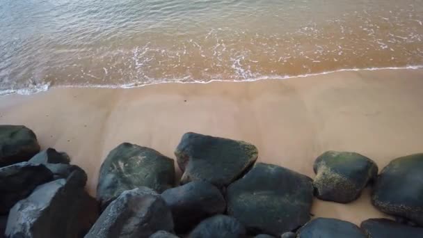 Widok z lotu ptaka na piaszczystą plażę i czysty ocean. Top view fale morskie i czarne kamienie 4k wideo, tropikalna piaszczysta plaża i fale, jest wschód słońca na Maderze. — Wideo stockowe