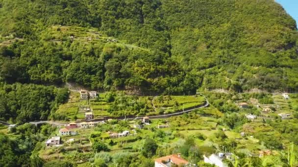 4k wideo z niesamowitym widokiem na szczyty górskie Madery. Tropikalny zielony krajobraz, budynki w wioskach otoczone są zielonymi lasami dzikiej przyrody. — Wideo stockowe
