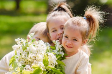 Baharda doğada üç çocuğun portresi.