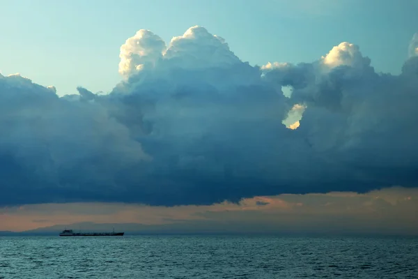 Barco cruzando el océano en una puesta de sol con rayos de sol, cielo realzado — Foto de Stock