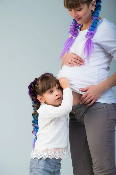 Забавная маленькая девочка слушает беременный живот — стоковое фото