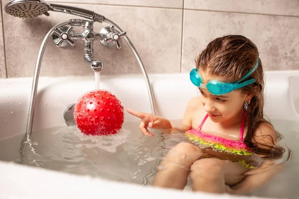 穿着泳衣笑着的小女孩喜欢在洗澡时玩球 家庭的概念在大肠病毒感染的时代就存在了 复制空间 — 图库照片