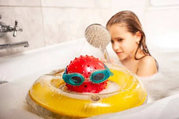 有趣的身份不明的小女孩一边洗澡一边在家里的浴室里洗澡 一边用一个球洗头和在浴室里游泳的护目镜 幼稚幻想的概念 — 图库照片