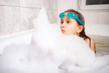 Yüzme gözlüklü güzel mavi gözlü küçük kız evde Coronavirus sırasında köpük banyosunda banyo yapıyor. Ev kavramında Chidrens oyunları