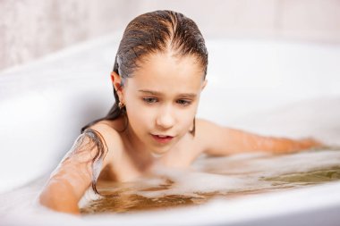Küçük beyaz kız köpükle küvette banyo yapıyor ve evde karantina sırasında eğleniyor. Hijyen ve çocuk sağlığı konsepti. Kopyalama alanı