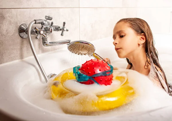 有趣的身份不明的小女孩一边洗澡一边在家里的浴室里洗澡 一边用一个球洗头和在浴室里游泳的护目镜 幼稚幻想的概念 — 图库照片