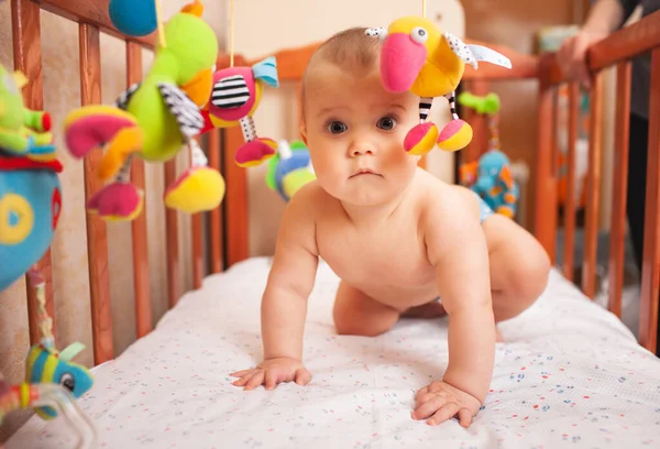 Menina Caucasiana Grave Rasteja Seu Berço Aconchegante Com Brinquedos Olha — Fotografia de Stock