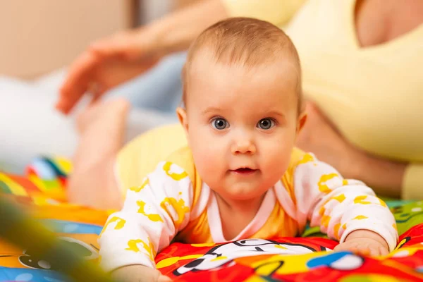 思いやりのある美しい若い母親のクローズアップは 居心地の良い子供部屋に横たわっている彼女の6ヶ月の魅力的な娘の色を教えています ケアと親の愛の概念 — ストック写真