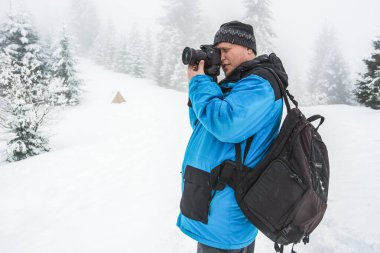Bir adam karlı bir ormanda duran birinin ya da bir şeyin fotoğrafını çeker. Güzel kış doğası. Karlı ormanda fotoğrafçı