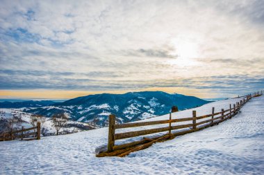 Dağların güzel manzarası karla kaplı ve bulutlu gökyüzüne ve günbatımına bakan yürüyüş yollarına bölünmüş durumda. Reklam için yer var. Dağ turizmi kavramı