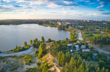 Mavi göl, çam ormanı, büyük şehir ve bulutlu güzel gökyüzü.