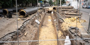 Yaz günü şehir yolunda yeni izole edilmiş siyah su boruları ve beton döşemeler. Şehir kanalizasyon altyapısı konsepti, yeraltı sisteminin modernizasyonu ve yeniden inşası.