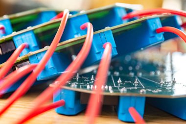 Askeri teçhizat fabrikasına bağlı kırmızı HI-voltaj kabloları ve mavi röleleri olan büyük yeşil bir mikro devreye yakın çekim. Üretimde yeni HI-voltaj teknolojileri kavramı