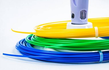 Beyaz üzerine izole edilmiş 3D yazıcı kalemlerin etrafındaki renkli kabloların yakın görüntüsü. Kapalı alanda duran üç parlak iplik plastiği. Çocukların eğlence ve yaratıcılığını kavrayın.