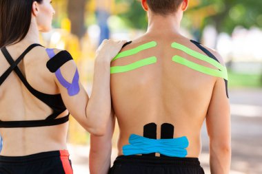 Spor sahasında poz veren kinezyolojik bantlı sporcular.