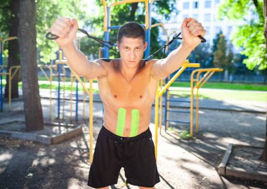 Açık havada elastik ip kullanarak yakışıklı erkek atlet eğitimi..