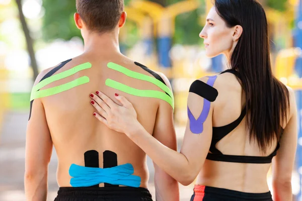 Atletas con cinta cinesiológica posando en campo deportivo. — Foto de Stock