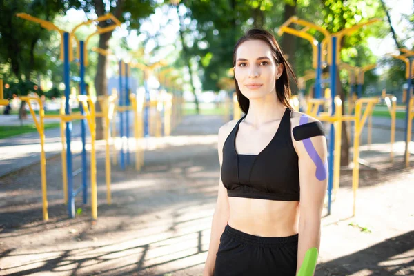 Mujer en forma con cinta cinesiológica posando al aire libre. — Foto de Stock