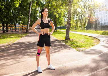 Spor kadını elleri belinde dışarıda poz veriyor..