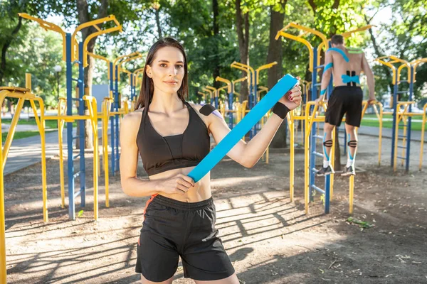 Mujer posando con cinta kinesiológica rollo posando al aire libre. — Foto de Stock