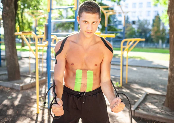 Bonito atleta masculino treinamento usando corda elástica ao ar livre. — Fotografia de Stock