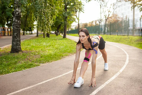 Mujer flexible con entrenamiento kinesiotaping en el parque. —  Fotos de Stock