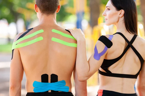 Spor sahasında poz veren kinezyolojik bantlı sporcular.