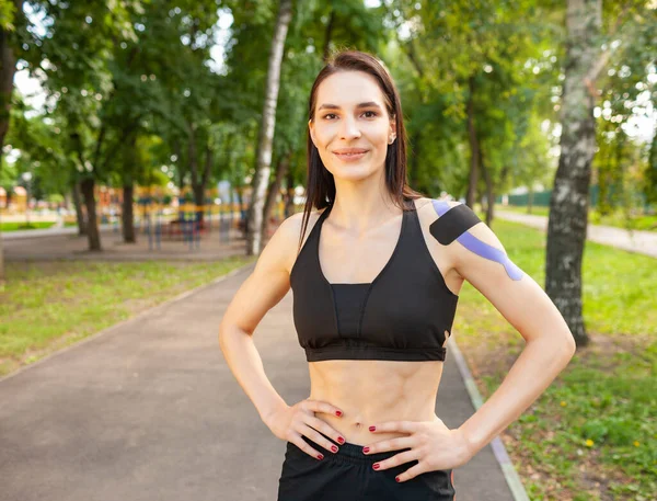 Mujer en forma con cinta cinesiológica posando al aire libre. — Foto de Stock