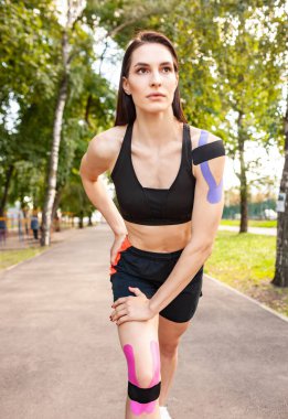 Kinesioteyp bantlı genç kadın dışarıda ısınıyor..