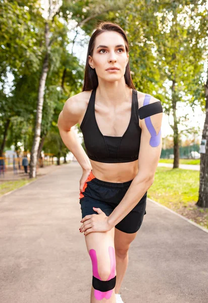 Kinesioteyp bantlı genç kadın dışarıda ısınıyor..