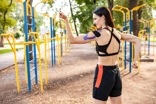 Atleta profesional femenina con cinta cinesiológica posando al aire libre. — Foto de Stock