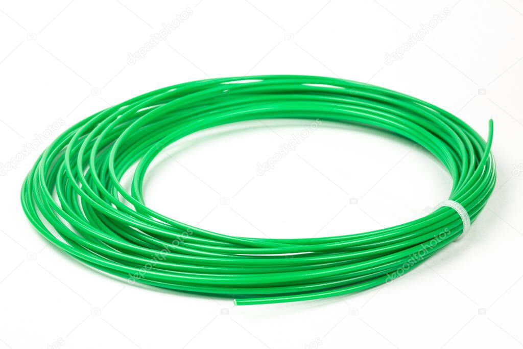 Top view of green rolled filament 3D pen PLA isolated on white. Closeup of plastic bright wire for 3D printer lying indoors. Concept of children's entertainment and creativity.