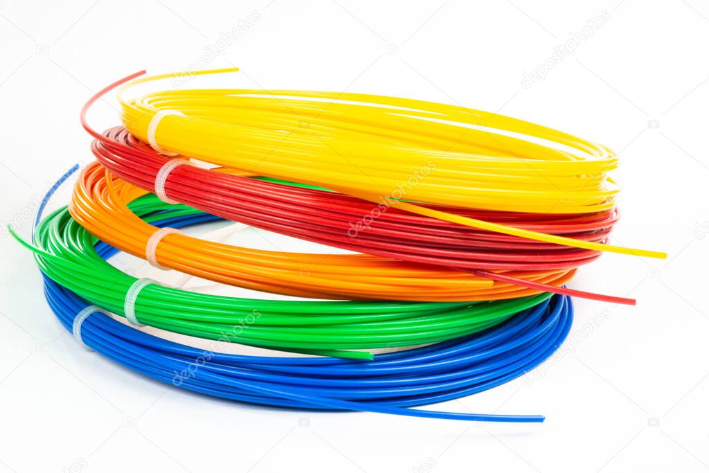 Top view of of four colorful rolled filament 3D pen PLA isolated on white. Closeup of plastic bright wires for 3D printer lying indoors. Concept of children's entertainment and creativity.