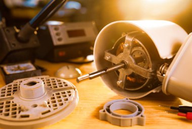 Evdeki soğutma vantilatörünün yakın çekimi önleyici temizlik, kayganlaştırma ve özel bir atölyede tamir sırasında bir masanın üzerinde yatar. Hasarlı ekipmanların onarımı ve restorasyonu