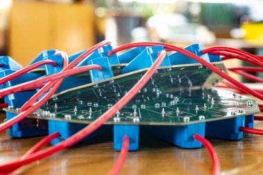 Askeri teçhizat fabrikasına bağlı kırmızı HI-voltaj kabloları ve mavi röleleri olan büyük yeşil bir mikro devreye yakın çekim. Üretimde yeni HI-voltaj teknolojileri kavramı