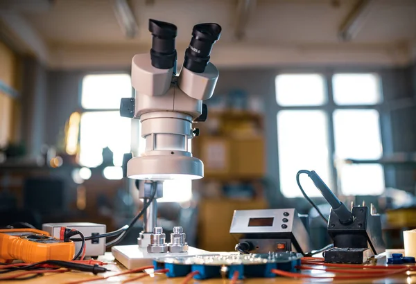 Large modern electron microscope. Microwave coaxial connector and electronic digital multimeter on workshop table. Research of high-frequency radio electronic components in a scientific laboratory