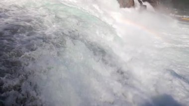 Hızlı fırtınalı soğuk su damlaları düşer ve küçük damlalar Rhine Şelaleleri 'ne İsviçre' deki eski kasabanın arka planına doğru farklı yönlere dağılır. 4k video yavaş çekim UHD