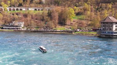 Turistler için büyük turist tekneleri, İsviçre 'deki eski kasabanın arka planına karşı bir sürü güzel beyaz nemli püskürtüyle ünlü Ren Şelalesi' nin yanında yüzüyor. 4k video yavaş çekim UHD