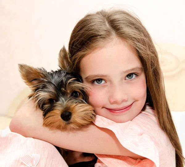 愛らしい笑みを浮かべて小さな女の子子供押し子犬ヨークシャー テリアと遊ぶ — ストック写真
