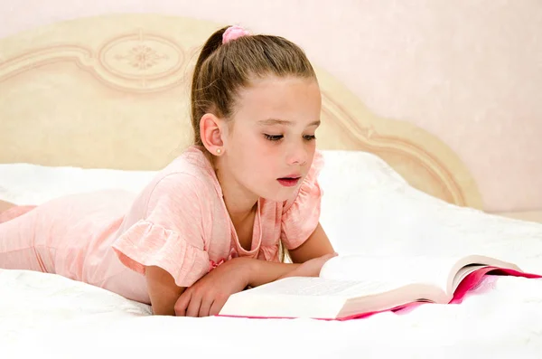 Entzückendes Kleines Mädchen Liest Ein Buch Auf Dem Bett — Stockfoto