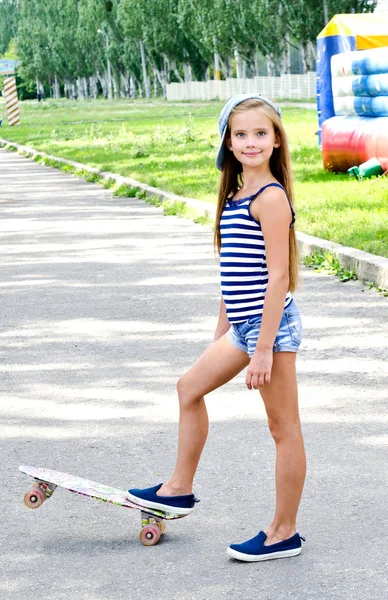 可爱的快乐微笑的小女孩与滑板户外在夏天的一天 — 图库照片
