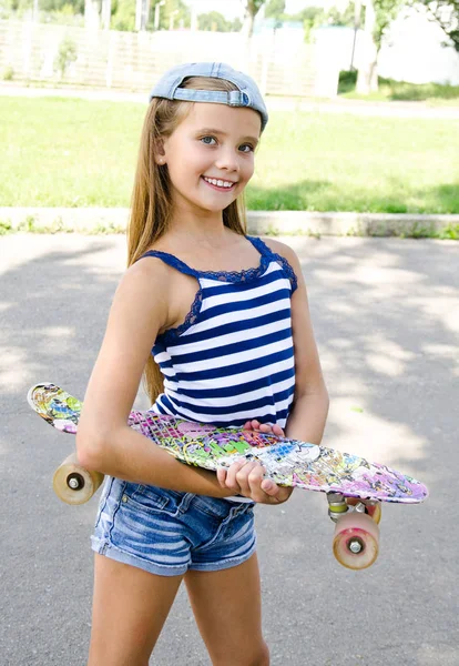 愛らしい幸せな笑みを浮かべて小さな女の子子夏の日の屋外のスケート ボードと — ストック写真