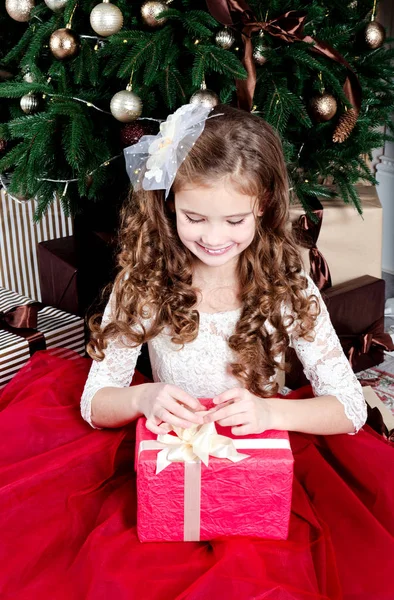 可爱的快乐微笑小女孩在公主礼服与礼物盒在冷杉树在圣诞节时间 — 图库照片