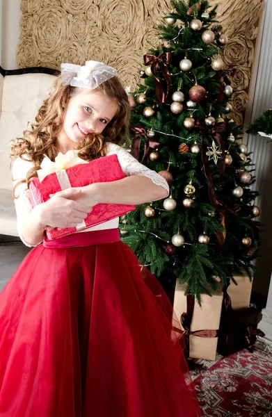 可爱的快乐微笑小女孩在公主礼服与礼物盒在冷杉树在圣诞节时间 — 图库照片