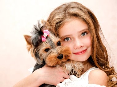 Holding ve köpek yavrusu yorkshire terrier ile oynayan sevimli gülümseyen küçük kız çocuğu 