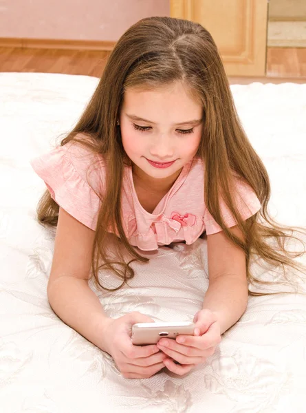 Schattig Meisje Kind Lachend Met Haar Mobiele Telefoon Smartphone Liggend — Stockfoto