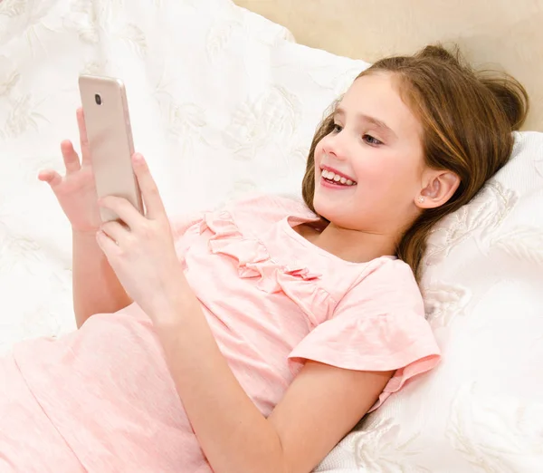 Schattig Meisje Kind Lachend Met Haar Mobiele Telefoon Smartphone Liggend — Stockfoto