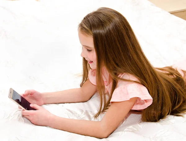Schattig Meisje Kind Lachend Met Haar Mobiele Telefoon Smartphone Liggend — Stockfoto