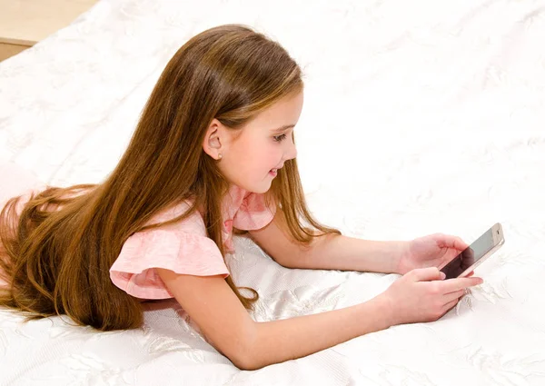 Schattig Meisje Kind Lachend Met Haar Mobiele Telefoon Smartphone Liggend — Stockfoto