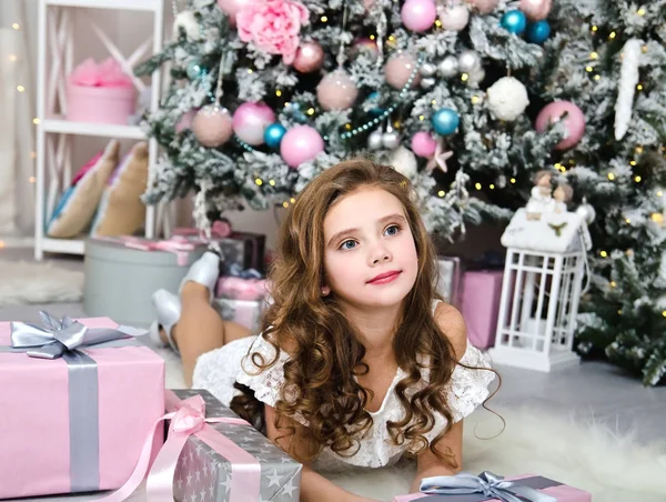 可爱的快乐微笑的小女孩的肖像在公主礼服与礼品盒躺在冷杉树附近在圣诞节时间 — 图库照片